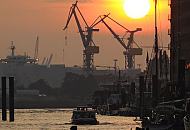10_26040 Blick ber den Sandtorhafen, dem Hamburger Traditionsschiffhafen zur Elbe - Barkassen fahren in der Abenddmmerung ber das Wasser. Der Himmel ist rot gefrbt - Krne stehen auf der gegenberliegenden Seite des Flusses.  