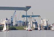 32_7444 Die Elbe bei Neuenfelde - an der Klappbrcke und dem Este- Sperrwerk (re.) legt gerade die Fhre nach Hamburg Blankenese zum gegenberliegenden Elbufer ab - Jollen segeln auf der Elbe. Hinter dem Elbdeich liegt die Sietas Werft mit der gewaltigen Krananlage und kleineren Rollkrnen; lks. liegt ein Frachtschiff im Dock, whrend re. die Aufbauten eines Schiffs zu erkennen ist, das am Este-Ufer der Werft im Werfthafen liegt.