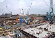 39_5191 Blick ber die Sietas-Werft in Hamburg Neuenfelde. Im Vordergrund liegt ein halbfertiges Schiffssegment, whrend hinter den Arbeitshallen die frisch gestrichenen Aufbauten ein Schiffsneubaus zu erkennen sind. 