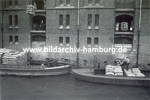01_15788 - historisches Aufnahme aus der Speicherstadt ca. 1935; Schuten liegen im Kanal / Fleet des Freihafens; sie sind mit Scke beladen. Mit dem Kran werden die Ladungen auf die einzelnen Etagen des Lagergebudes transportiert.