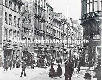 04_22731 Blick in den Neuen Wall ca. 1920; Passanten berqueren die Strasse, eine Pferdekutsche wartet auf ihre Fahrgste - die Herren tragen Melone und Spazierstock.