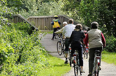11_21555 Eine Familie macht auf dem Billewanderweg eine Fahrradtour. Eine Holzbrcke fhrt die Fahrradfahrer und Fahrradfahrerinnen ber den Hamburger Fluss.