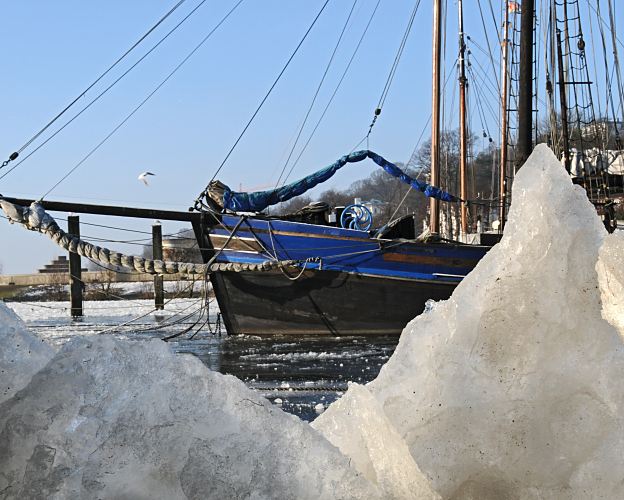 11_22737 Blick durch die Eisschollen im Museumshafen auf den Bugsprit eines historischen Segelschiffs. www.fotograf-hamburg.de  Bilder Hamburgs Winter - blauer Himmel, Eisschollen.