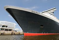 02_4353 Bug der Queen Mary 2 am Kreuzfahrtterminal im Hamburger Hafen. Schaulustige Hamburger stehen auf einer  Terrasse der Hafencity und bewundern das riesige Schiff. Die R.M.S. (Royal Mail Ship)  Queen Mary 2 (QM2) ist mit 148.528 BRZ eines der grten Passagierschiff der Welt. Das britische Kreuzfahrtschiff  hat eine Lnge von 345 m und eine Breite von 45 m. Der Luxusliner bietet in 1310 Kabinen bis zu 2.620 Passagieren Platz und hat eine Besatzung von 1.253 Personen. Die Queen Mary 2 hat fnf Swimmingpools, einen Ballsaal, Golfanlage, Wintergarten, Sportzentrum, mit ber 8.000 Bchern die grte Bibliothek auf See, den grten ffentlichen Saal (Restaurant Britannia), der ber zwei Decks und die gesamte Schiffsbreite geht, acht weitere Restaurants, Fitness-Center, Planetarium, Kino, Theater.  www.fotograf-hamburg.de