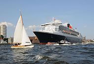 09_4392 Die Queen Mary 2 auf der Elbe vor Hamburg Neumhlen, viele Schiffe begleiten das riesige Passagierschiff; eine Segelyacht kreuzt vor dem Bug des Kreuzfahrtschiffs. Die R.M.S. (Royal Mail Ship)  Queen Mary 2 (QM2) ist mit 148.528 BRZ eines der grten Passagierschiff der Welt. Das britische Kreuzfahrtschiff  hat eine Lnge von 345 m und eine Breite von 45 m. Der Luxusliner bietet in 1310 Kabinen bis zu 2.620 Passagieren Platz und hat eine Besatzung von 1.253 Personen. Die Queen Mary 2 hat fnf Swimmingpools, einen Ballsaal, Golfanlage, Wintergarten, Sportzentrum, mit ber 8.000 Bchern die grte Bibliothek auf See, den grten ffentlichen Saal (Restaurant Britannia), der ber zwei Decks und die gesamte Schiffsbreite geht, acht weitere Restaurants, Fitness-Center, Planetarium, Kino, Theater.  www.fotograf- hamburg.de