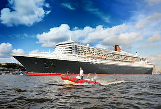 8582 Die 345m lange Queen Mary 2 verlsst Hamburg und fhrt Hhe Landungsbrcken - ein rotes Schlauchboot, Motorboot begleitet das Kreuzfahrtschiff auf der Elbe im Hamburger Hafen. 