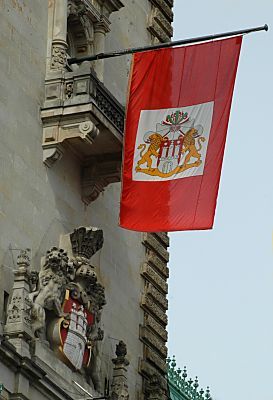 011_15415 - die Hamburger Staatsflagge am Rathaus, darunter das Wappen der Freien und Hansestadt Hamburg mit der stilisierten Burg.