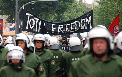 011_15695 - mehrere Reihen von behelmten Polizisten marschieren vor dem Demonstrationszug - Transparent " Total Freedom ".